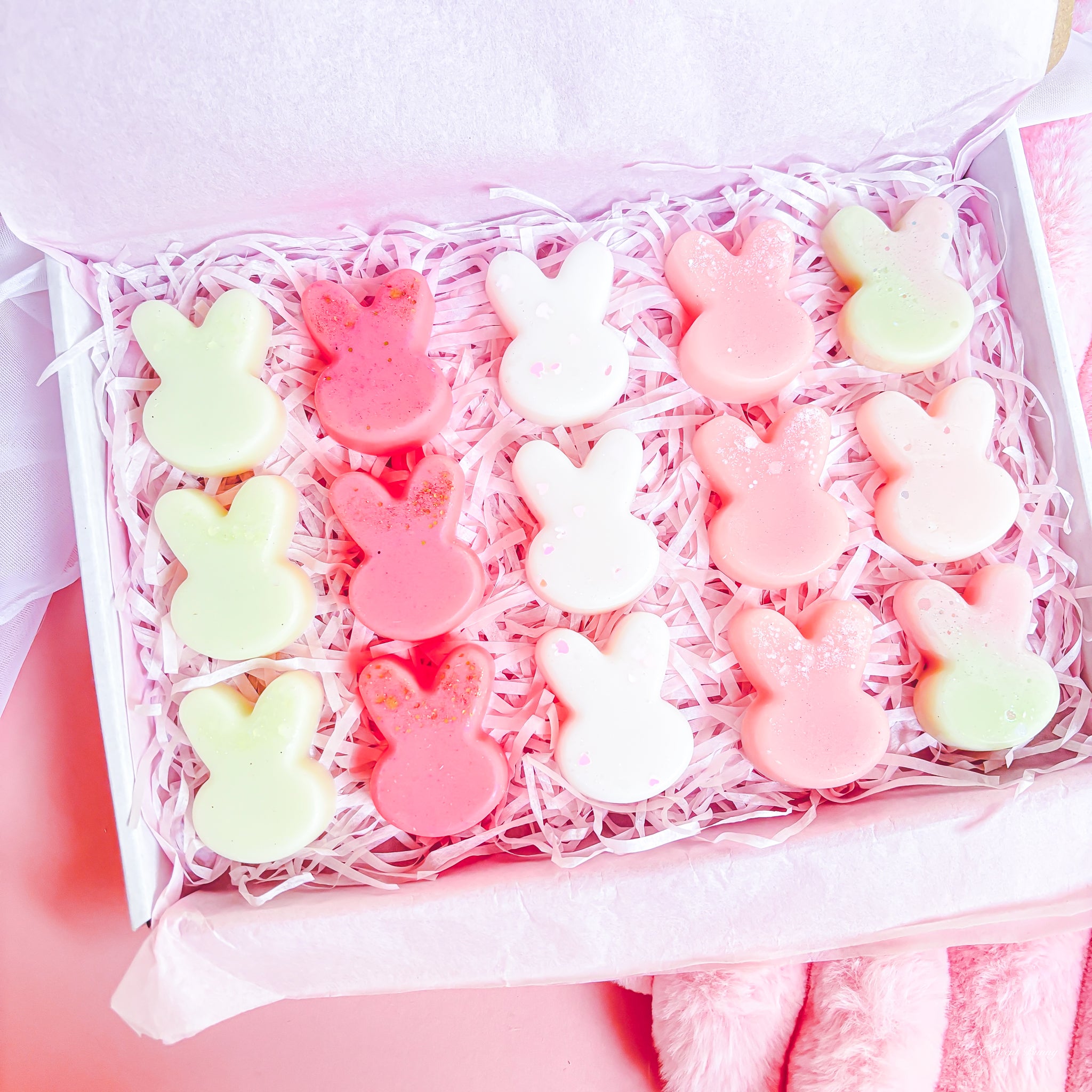 Box of colorful bunny-shaped candies on a pink background
